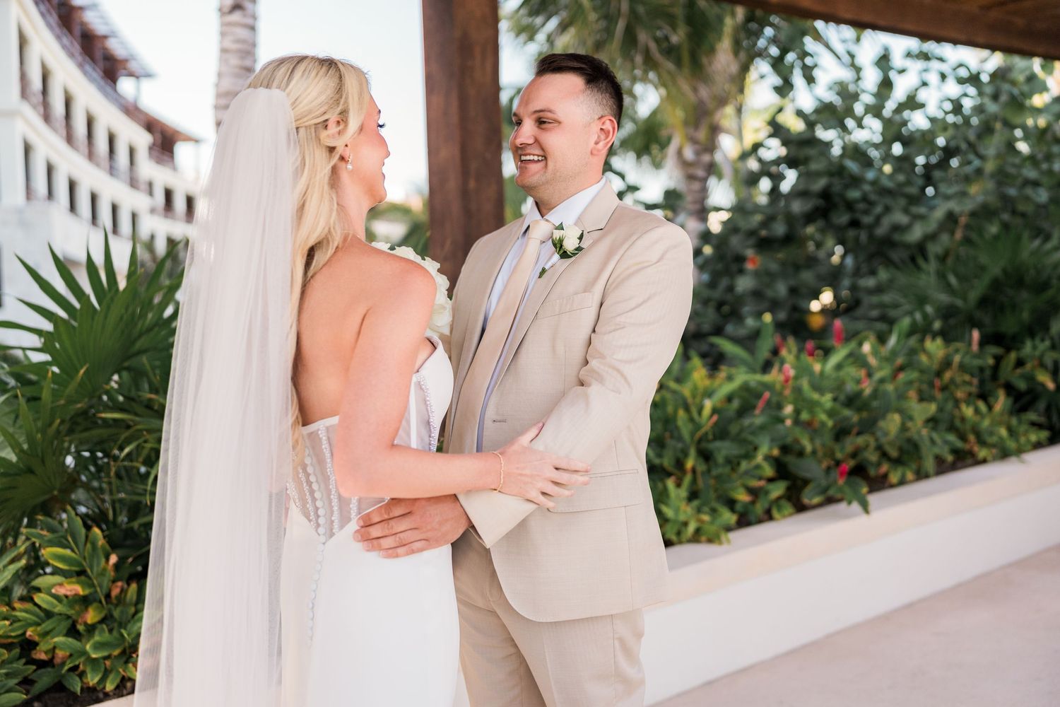 Bride and groom smile at each other during first look at lush tropical destination wedding.