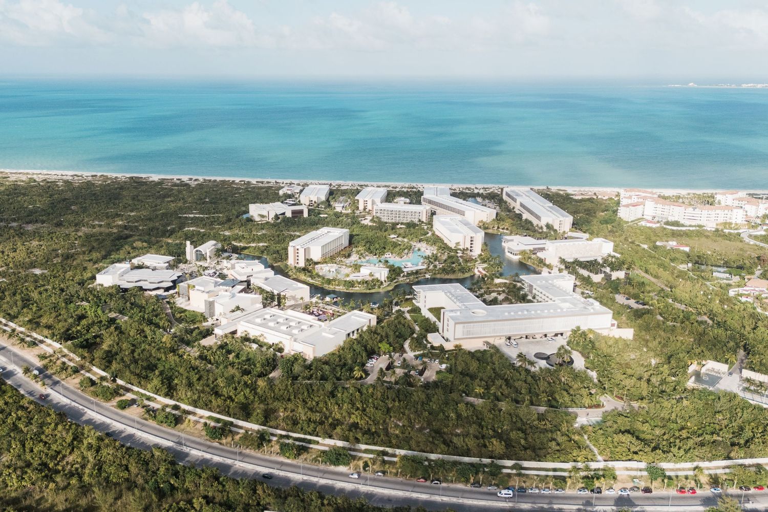 Aerial view of a grand palladium costa mujeres surrounded by lush tropical greenery with turquoise ocean views.