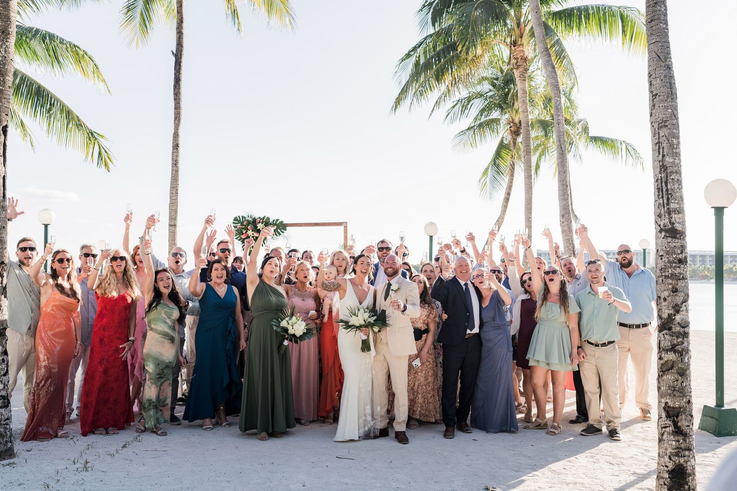 Wedding party cheering in colorful attire at a sunny outdoor ceremony. Puerto Vallarta wedding photographer