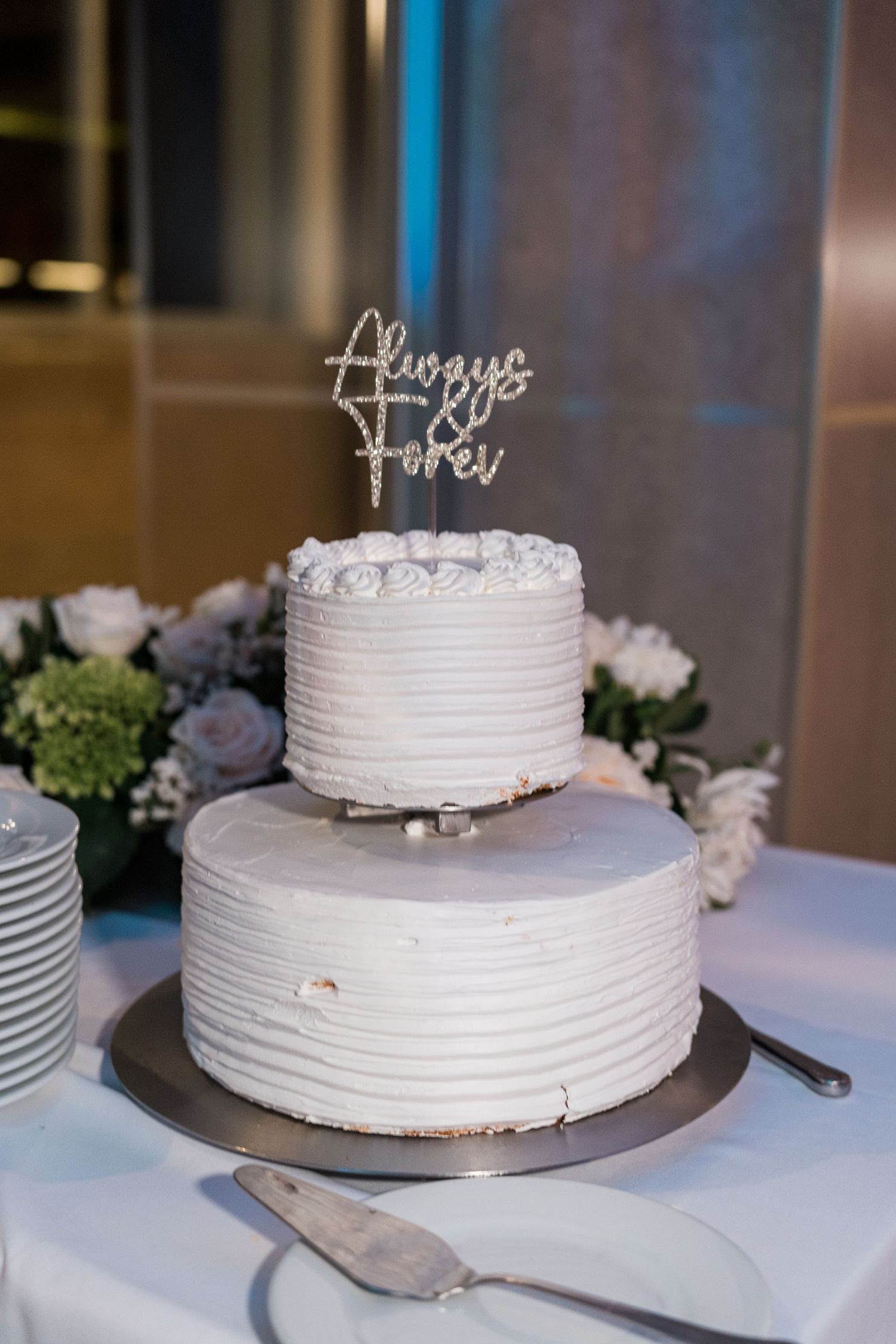 Elegant two-tier white wedding cake with Always and Forever rhinestone cake topper.