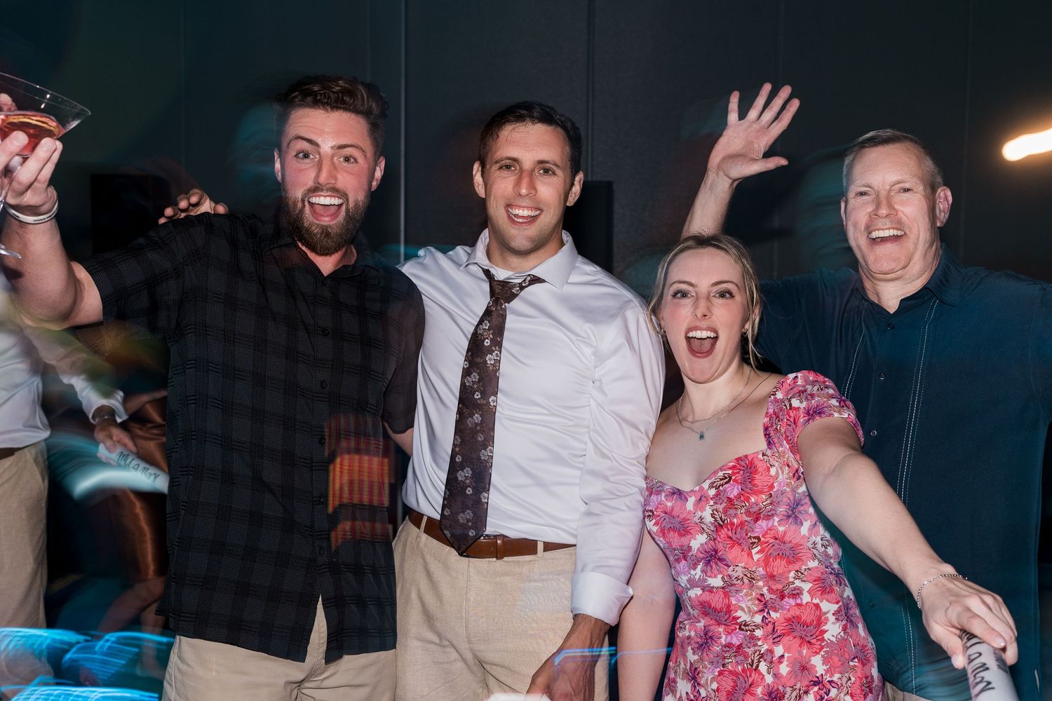 Group of four guests smiling and celebrating at a wedding reception party.