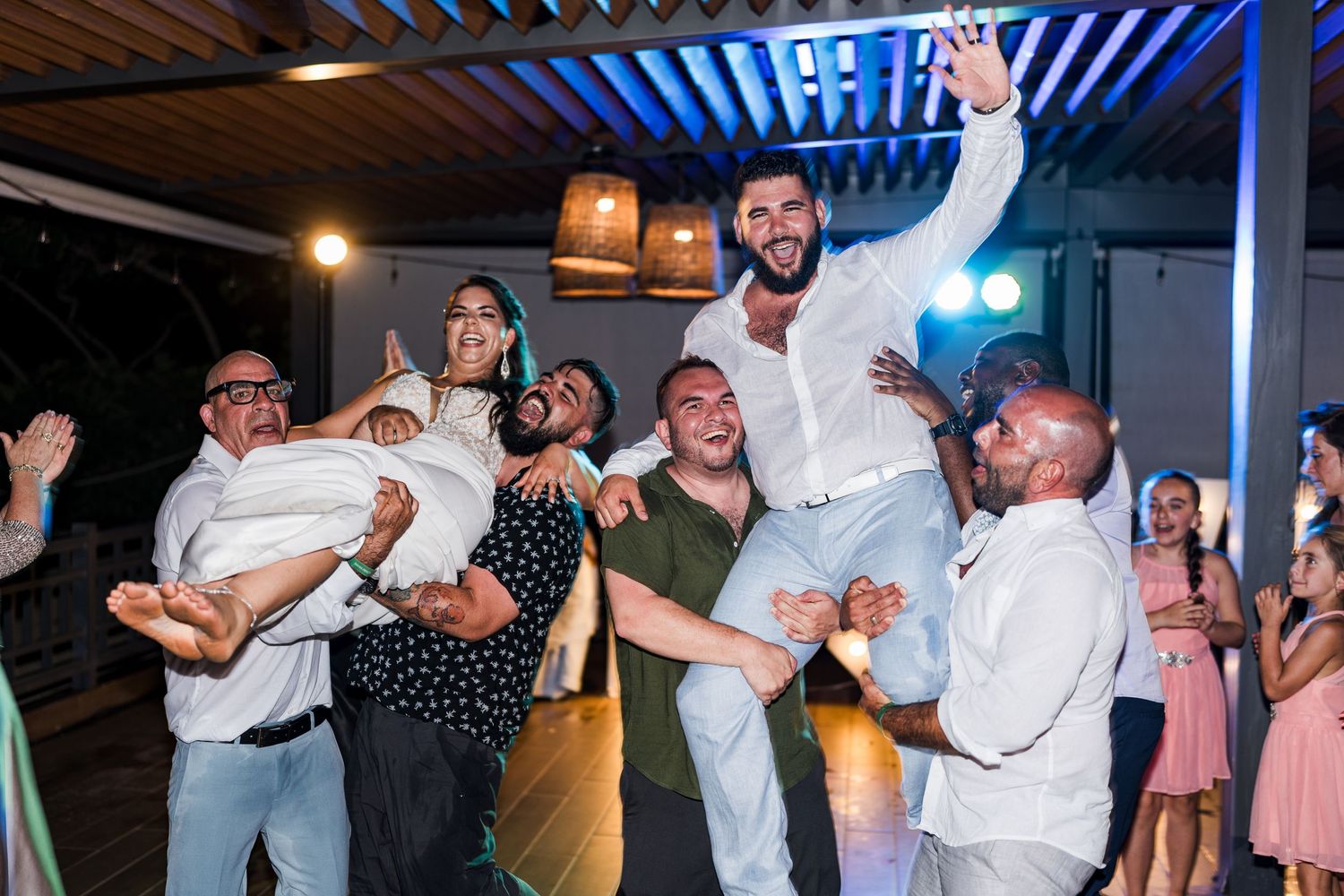 Groom lifted by groomsmen in a celebratory moment on the wedding reception dance floor.