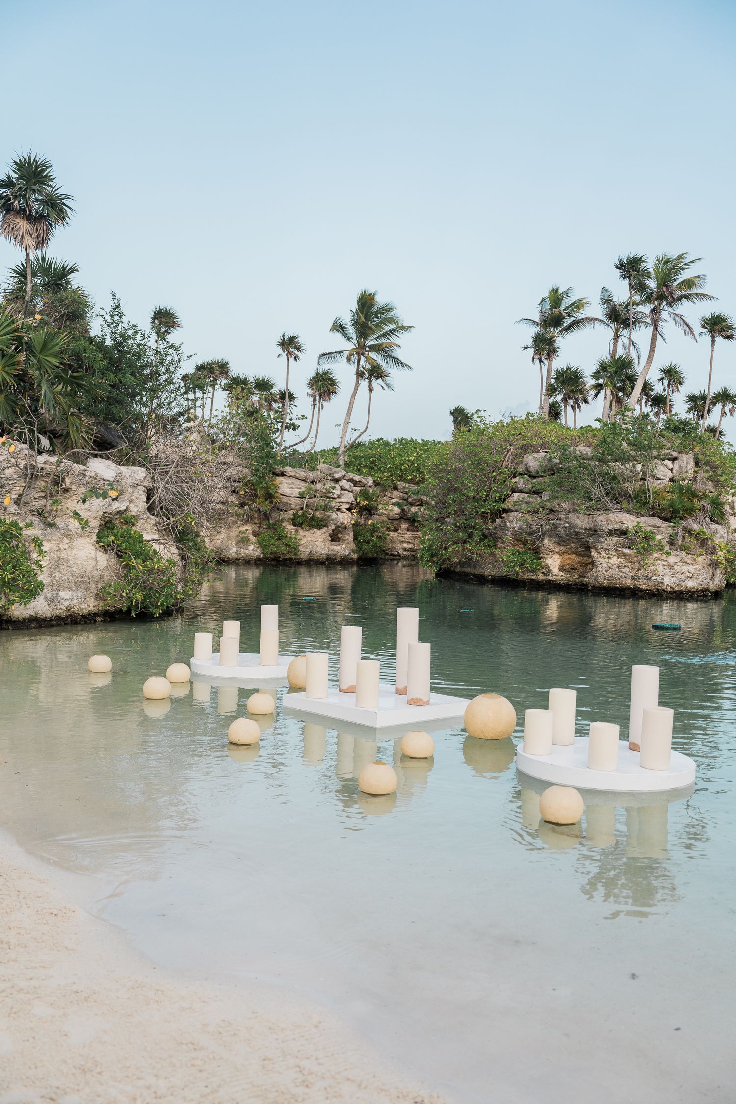 Hotel Xcaret México White decorative platforms with cylindrical pillars float on a serene lagoon