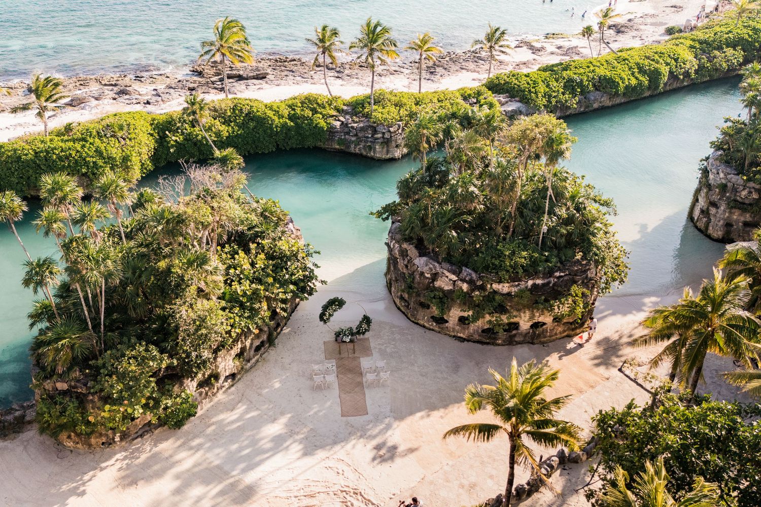 Aerial view of a tropical resort Xcaret mexico with lush palm trees, turquoise water, and sandy beach along a scenic coastline.