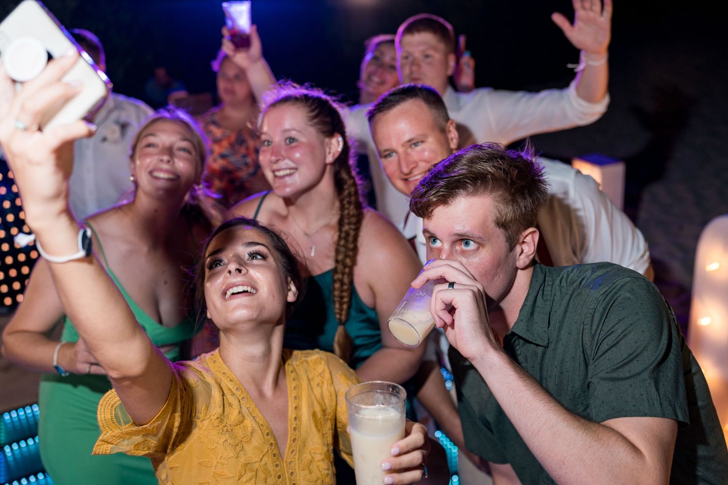 Group of friends taking a selfie at a lively wedding reception party.