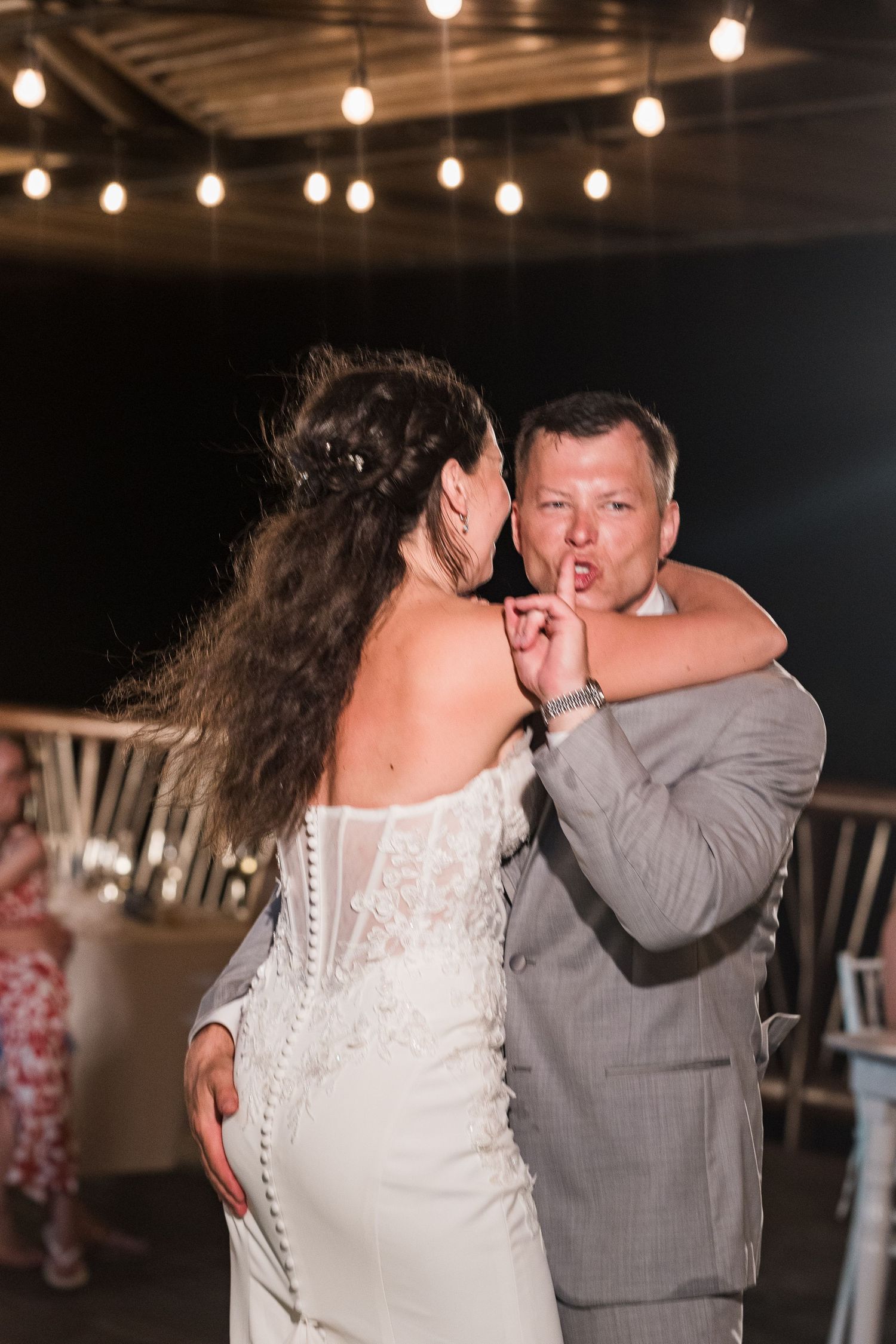 Bride and groom share an intimate first dance under string lights at their outdoor wedding reception.