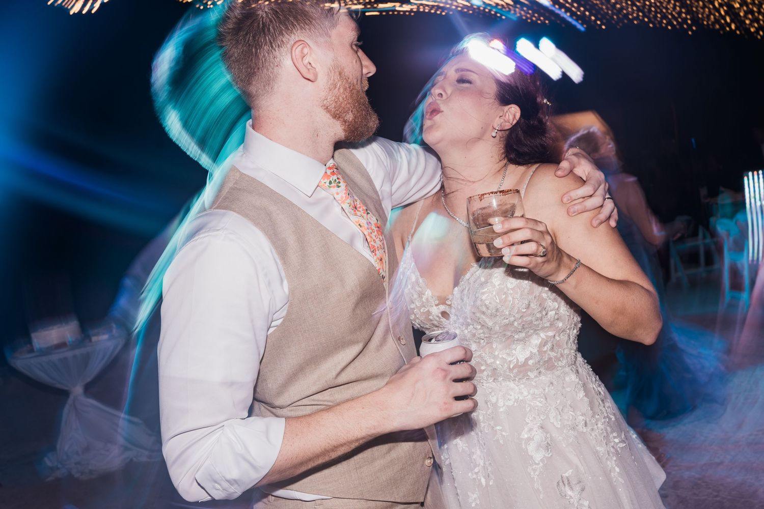Bride and groom share an intimate dance together at their wedding reception under blue lights.