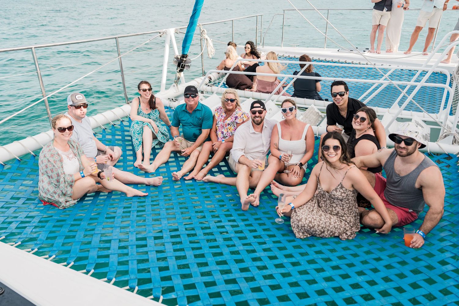 Group of friends relaxing on a catamaran boat deck on a sunny day at sea.