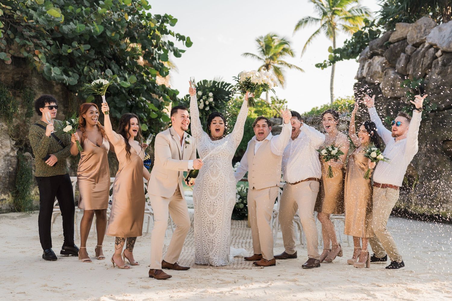 Xcaret Arte Wedding - Wedding party celebrates on a tropical beach, dressed in neutral beige tones