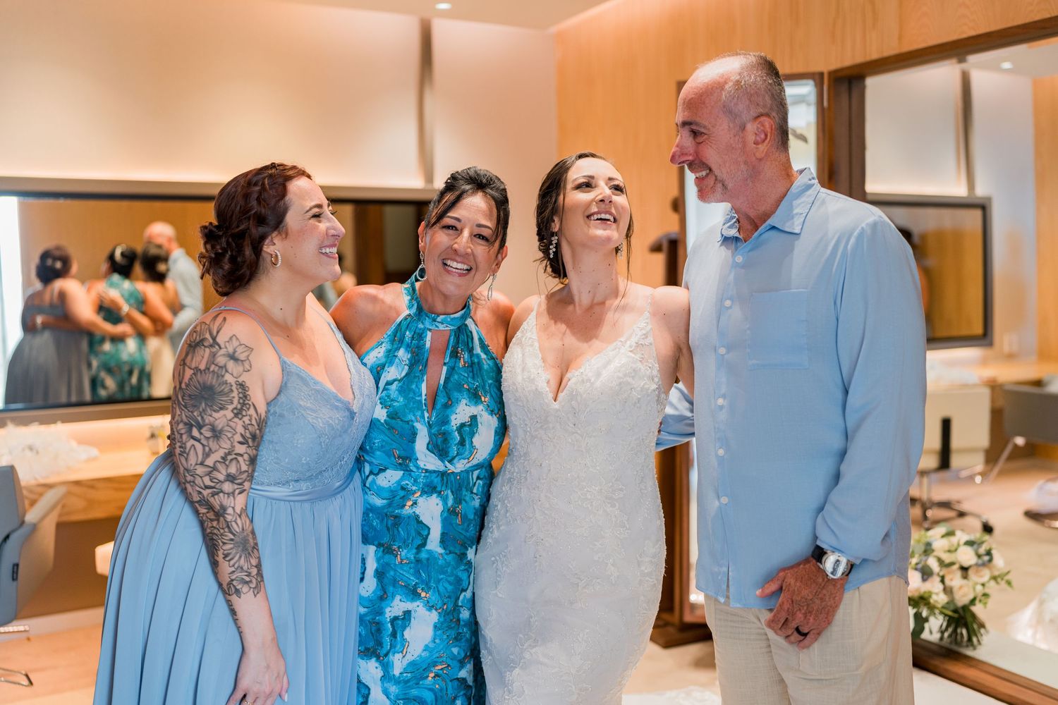 Bride poses joyfully with family including mother and father before wedding ceremony.