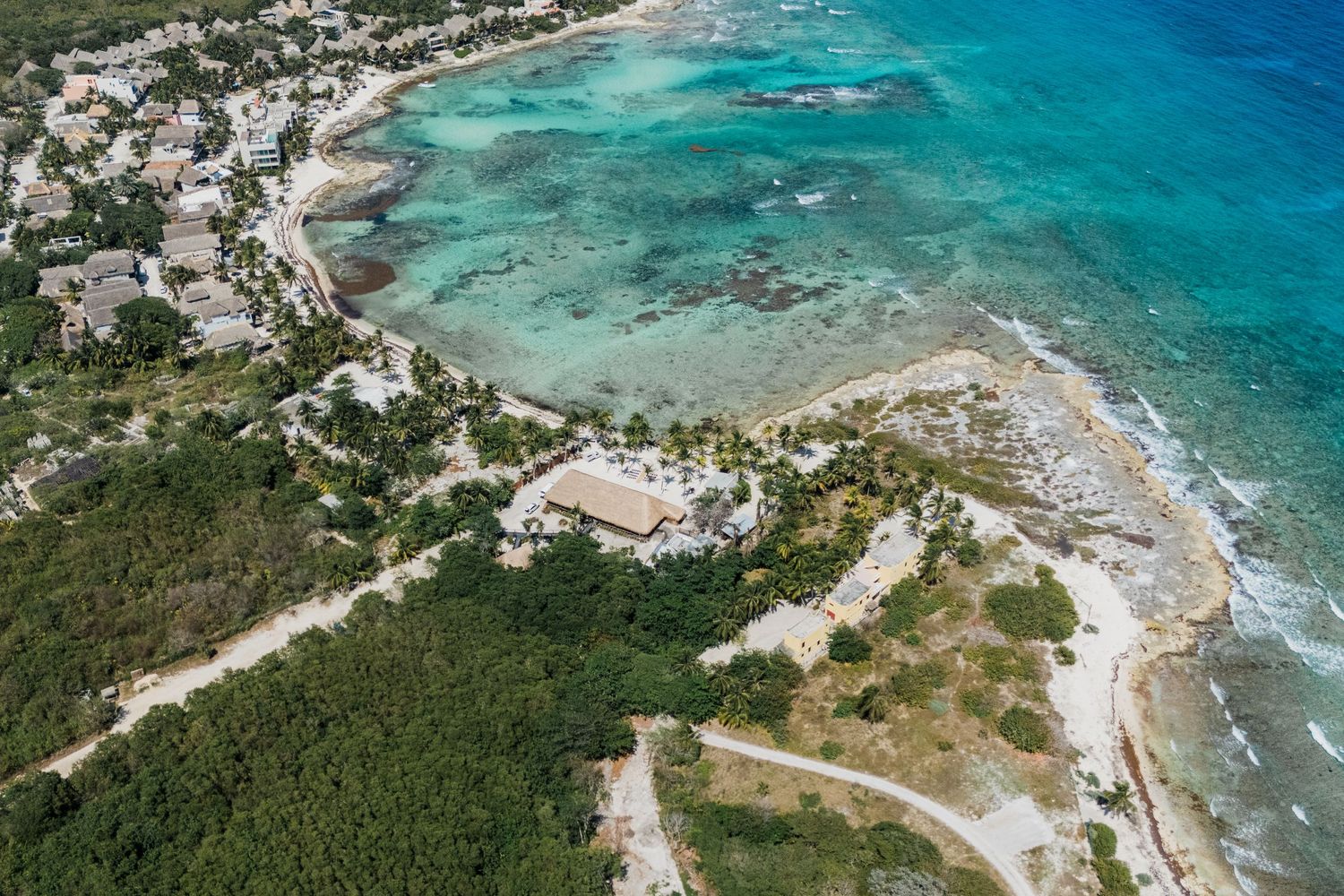 Aerial view of a tropical coastal wedding venue surrounded by turquoise Caribbean waters and lush greenery.