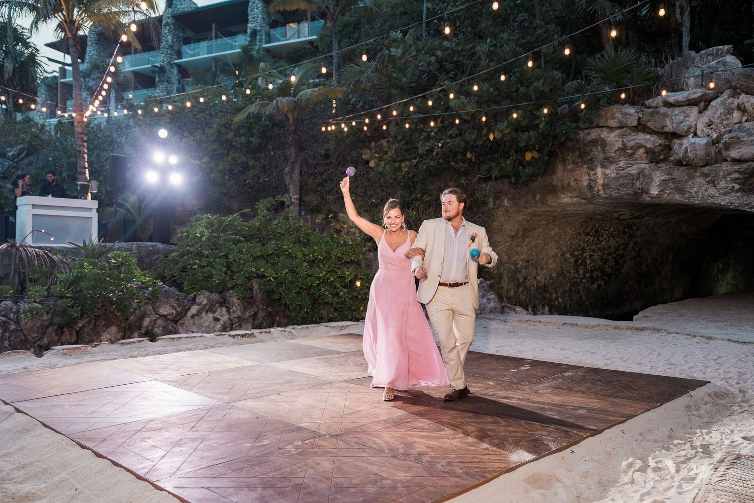 Hotel Xcaret México Couple dancing on outdoor dance floor at beach wedding reception with string lights and tropical backdrop at night.