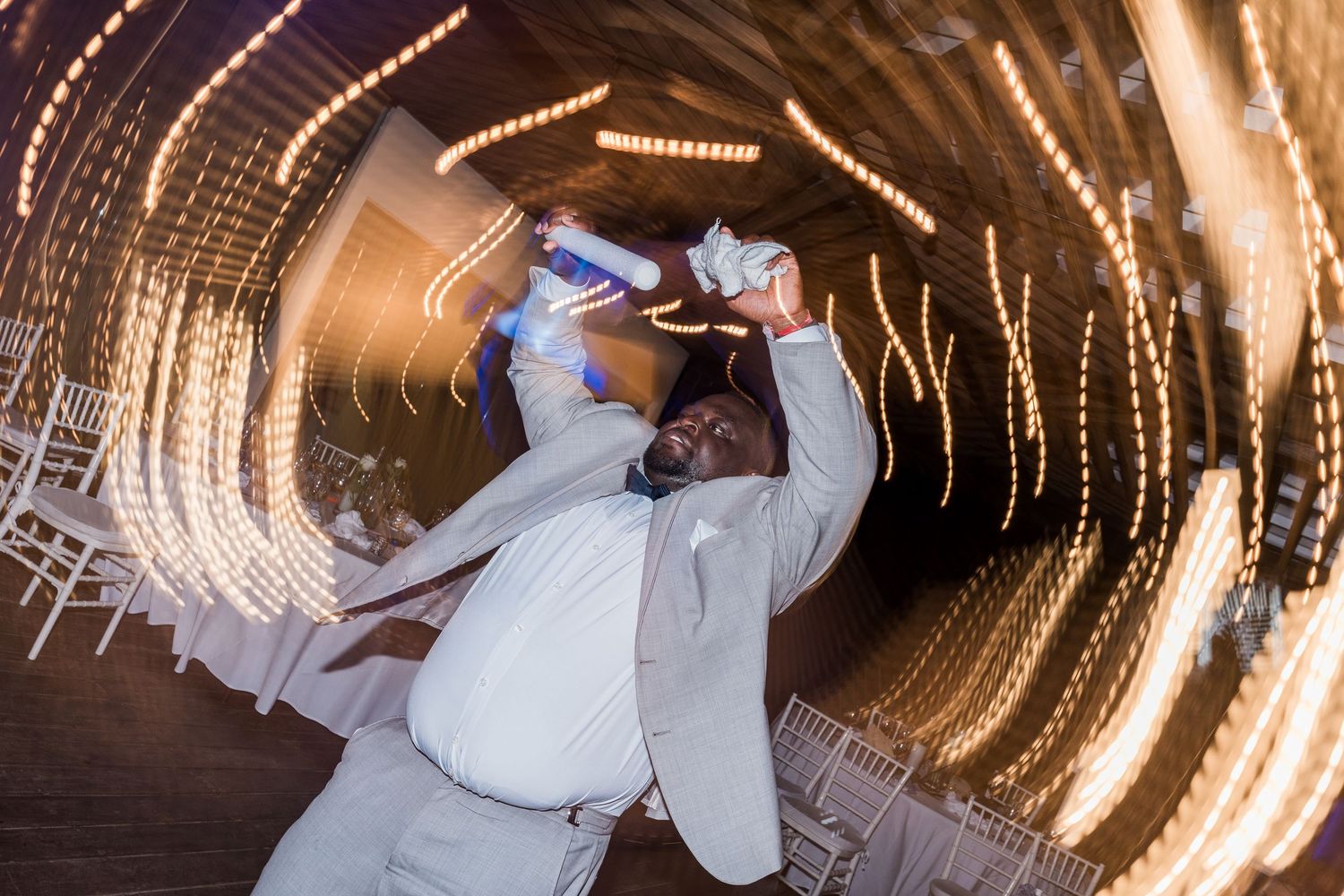 Man in white suit dancing energetically at a wedding In grand palladium costa mujeres