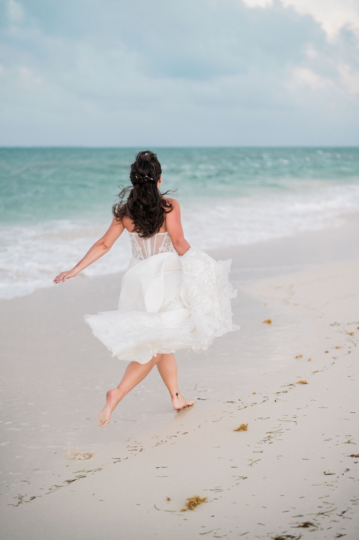 Bride in white wedding dress running barefoot on sandy beach grand palladium costa mujeres wedding
