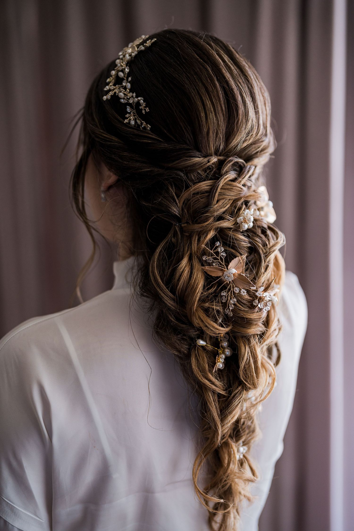 Bride's romantic braided hairstyle adorned with delicate pearl and crystal hair accessories.