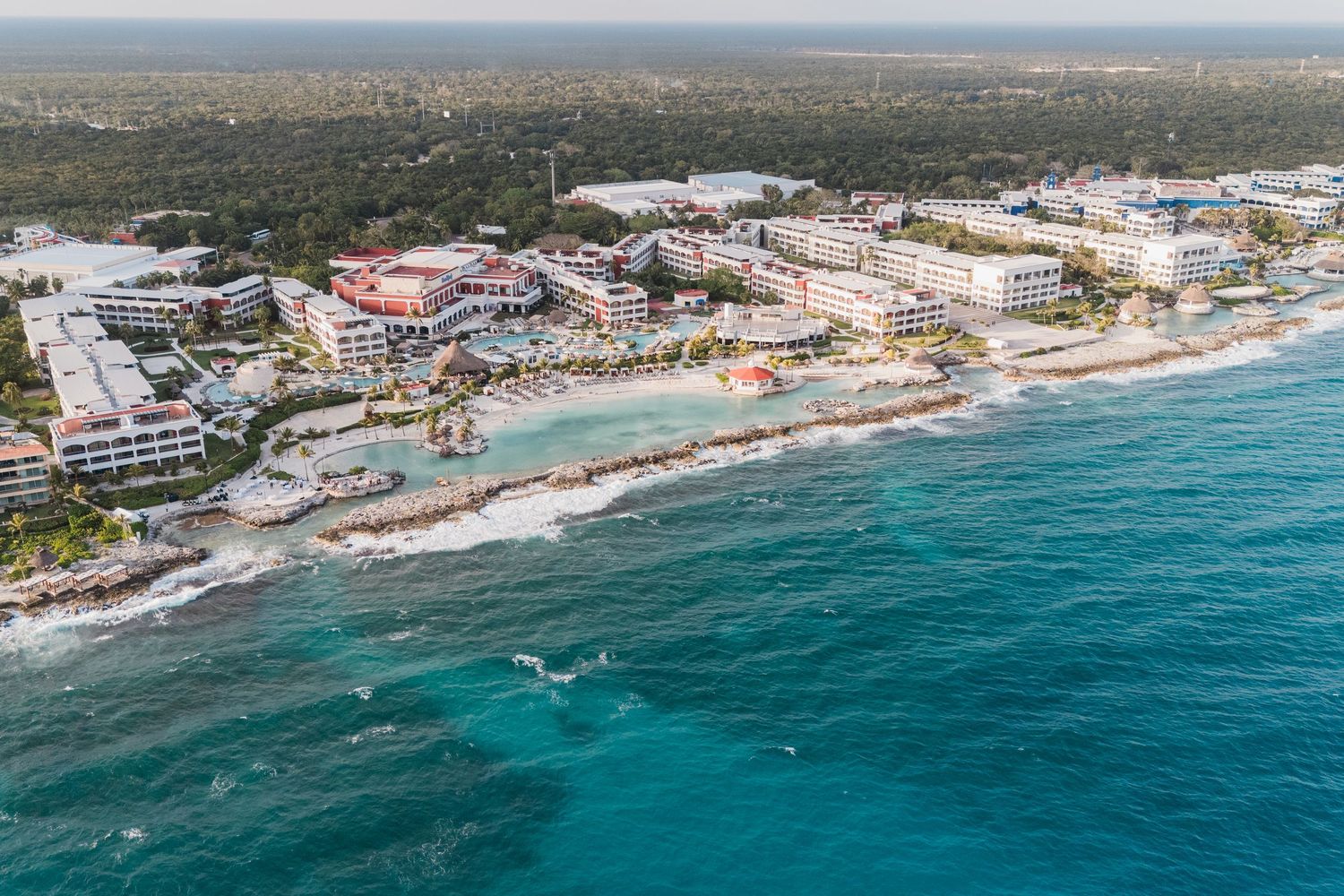 Aerial view of a luxury beachfront resort along the turquoise Caribbean coastline surrounded by lush jungle.