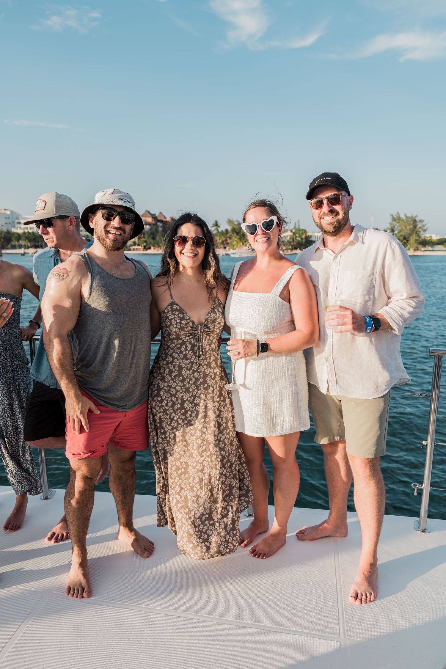 Group of friends posing together on a yacht deck near tropical waters on a sunny day.