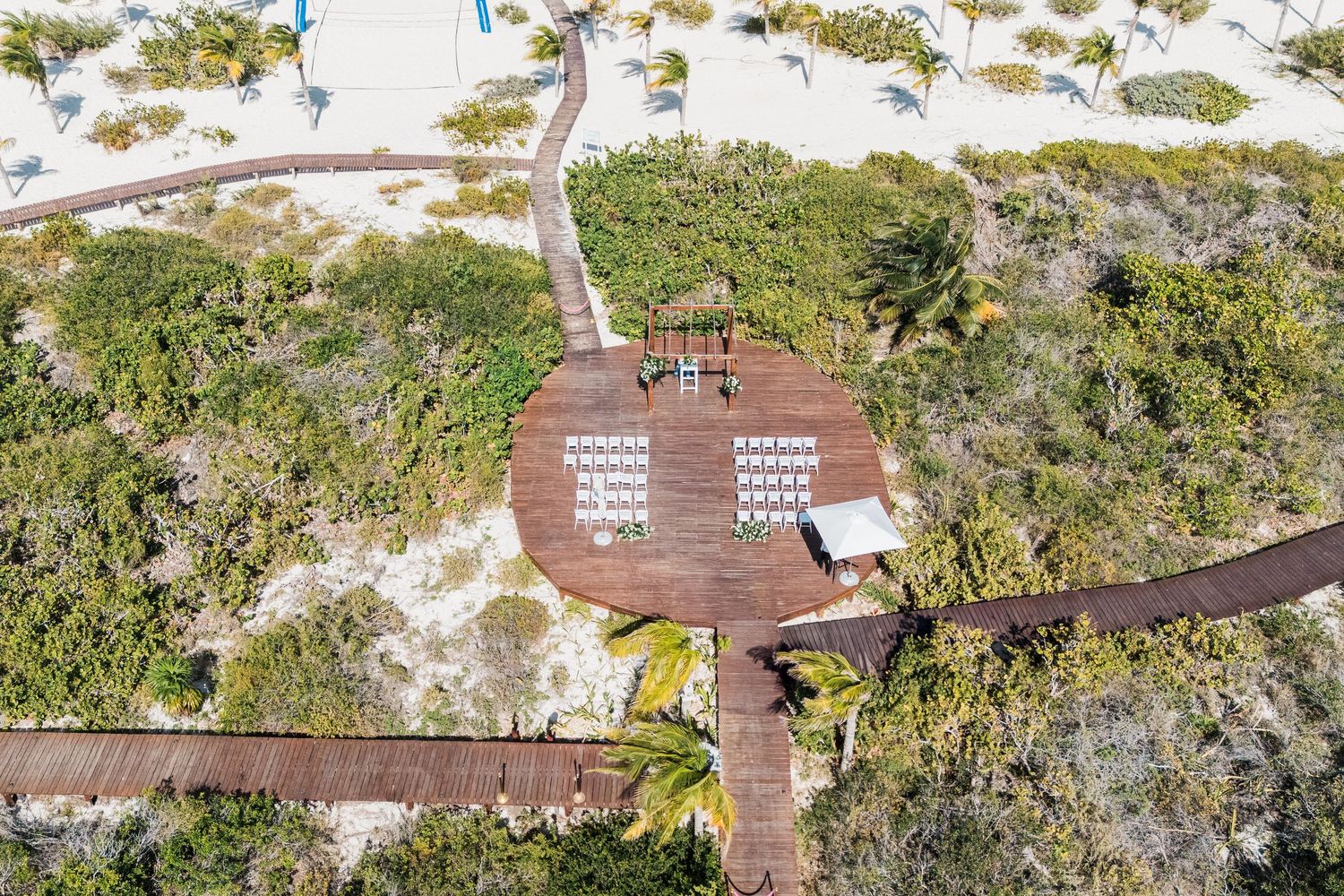 Aerial view of a beachside wooden deck ceremony setup at grand palladium costa mujeres wedding
