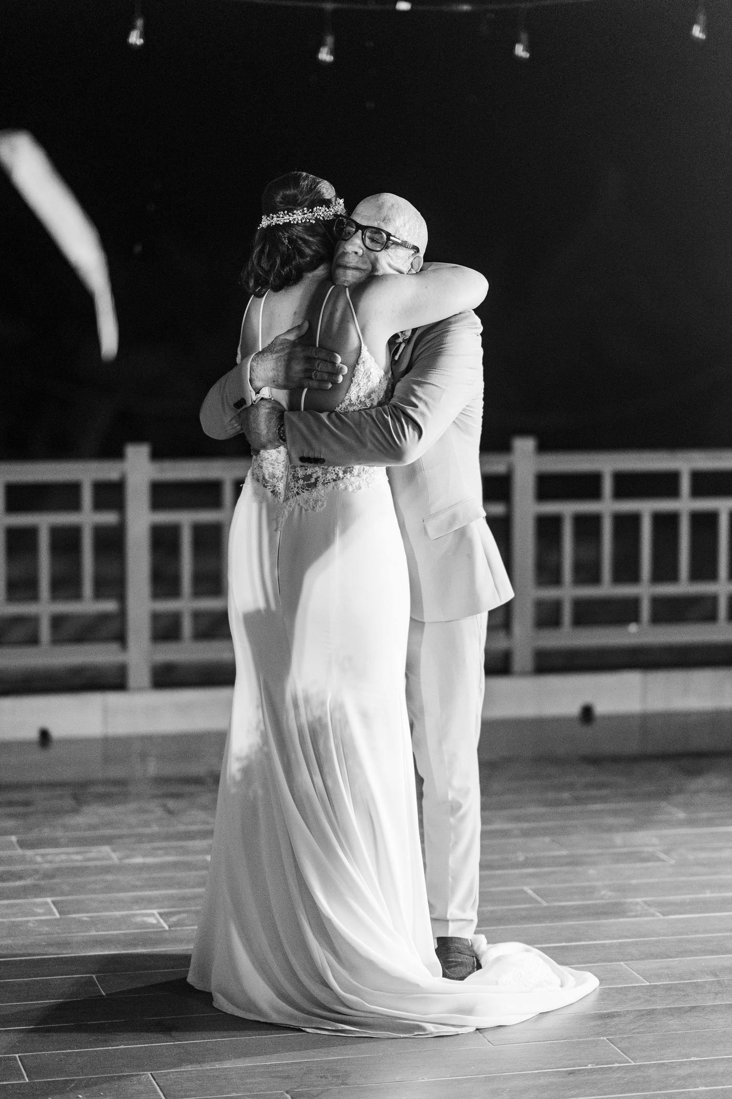 Bride and groom share an intimate embrace during first dance in elegant black and white wedding photo.