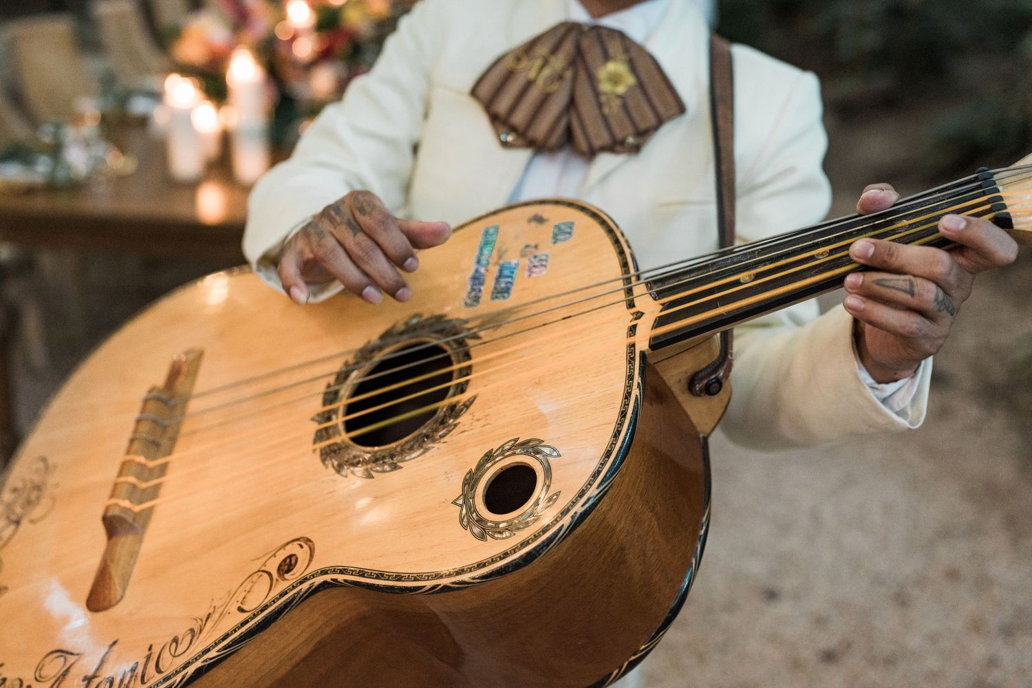 Secrets Akumal Wedding - Mariachi musician playing an ornate vihuela guitar, wearing traditional white charro suit at a festive event.
