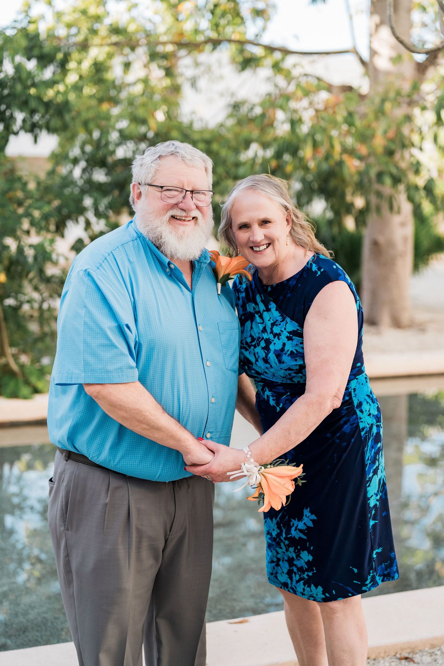 Secrets Akumal Wedding - Smiling older couple holding hands outdoors near a pool,