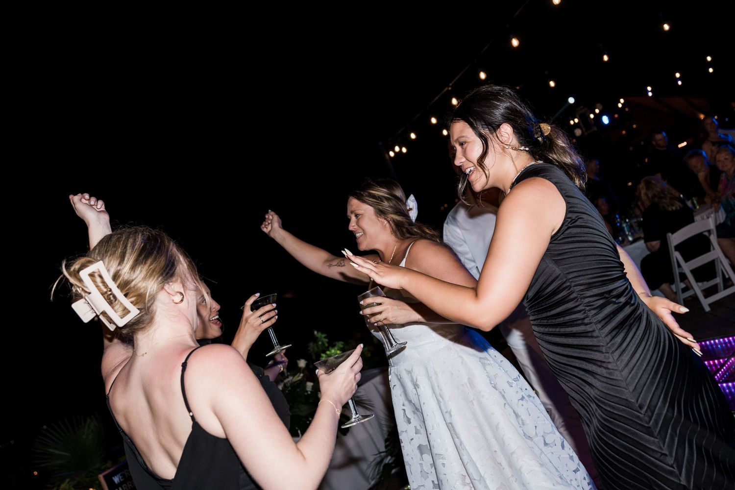 Women dancing and celebrating at an outdoor evening wedding reception party.