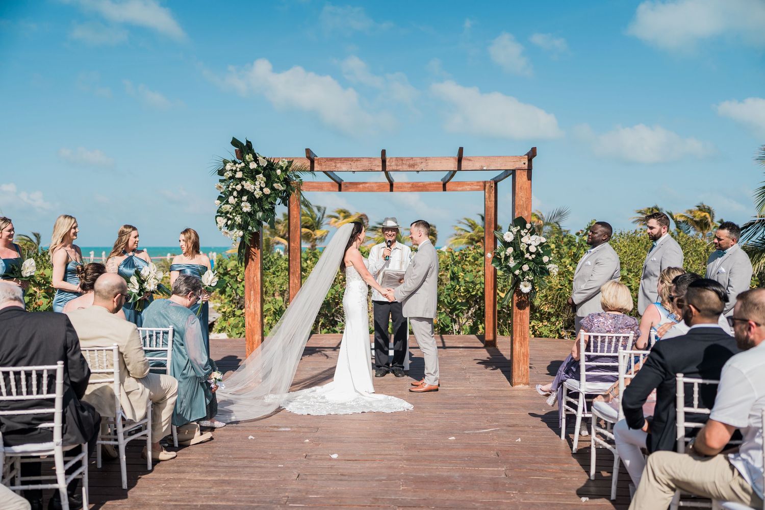 Outdoor beach wedding ceremony with couple at wooden arch at grand palladium costa mujeres wedding