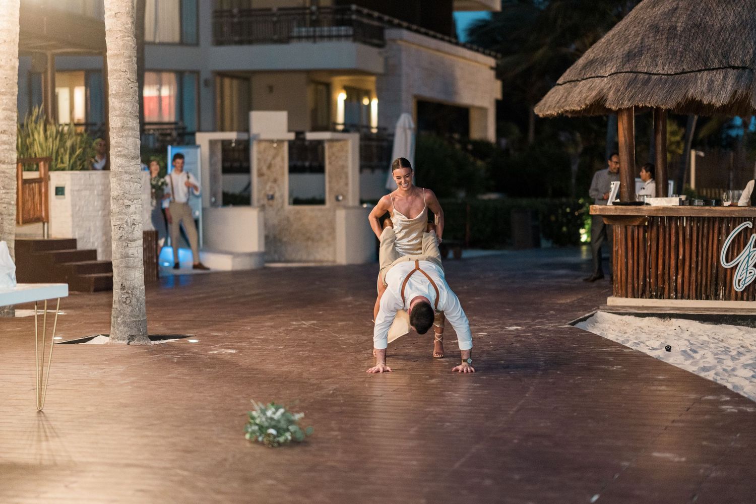 Guest performing a dance move at an outdoor resort wedding reception at dusk.