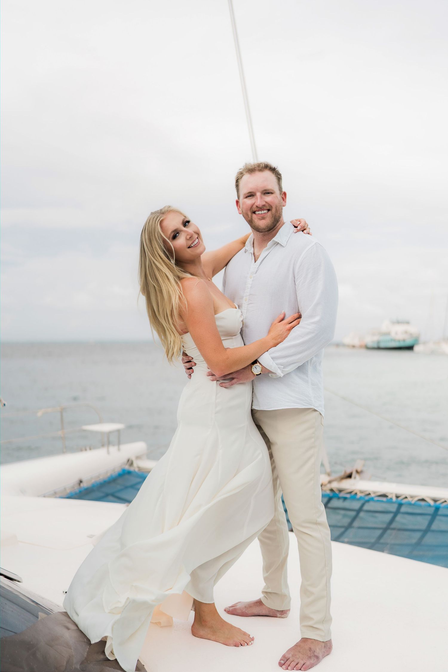Cancun Engagement Photoshoot - Cancun Engagement Photoshoot - Couple in white outfits embracing on a catamaran deck with ocean views