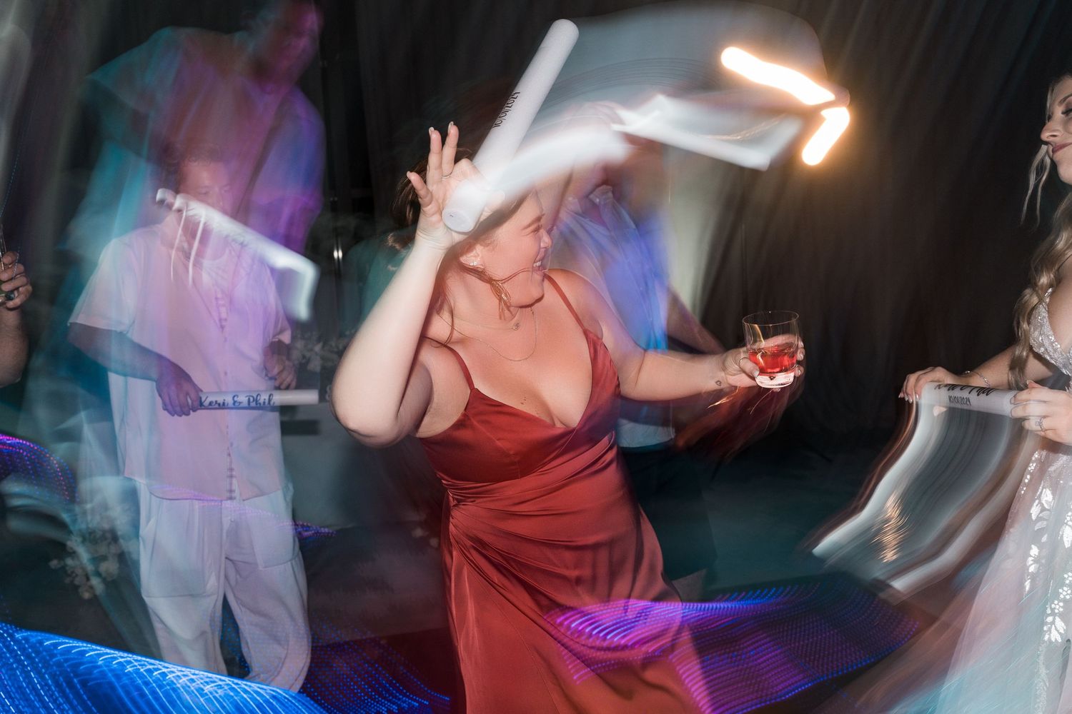 A guest in a red dress dances energetically at a lively wedding reception party.