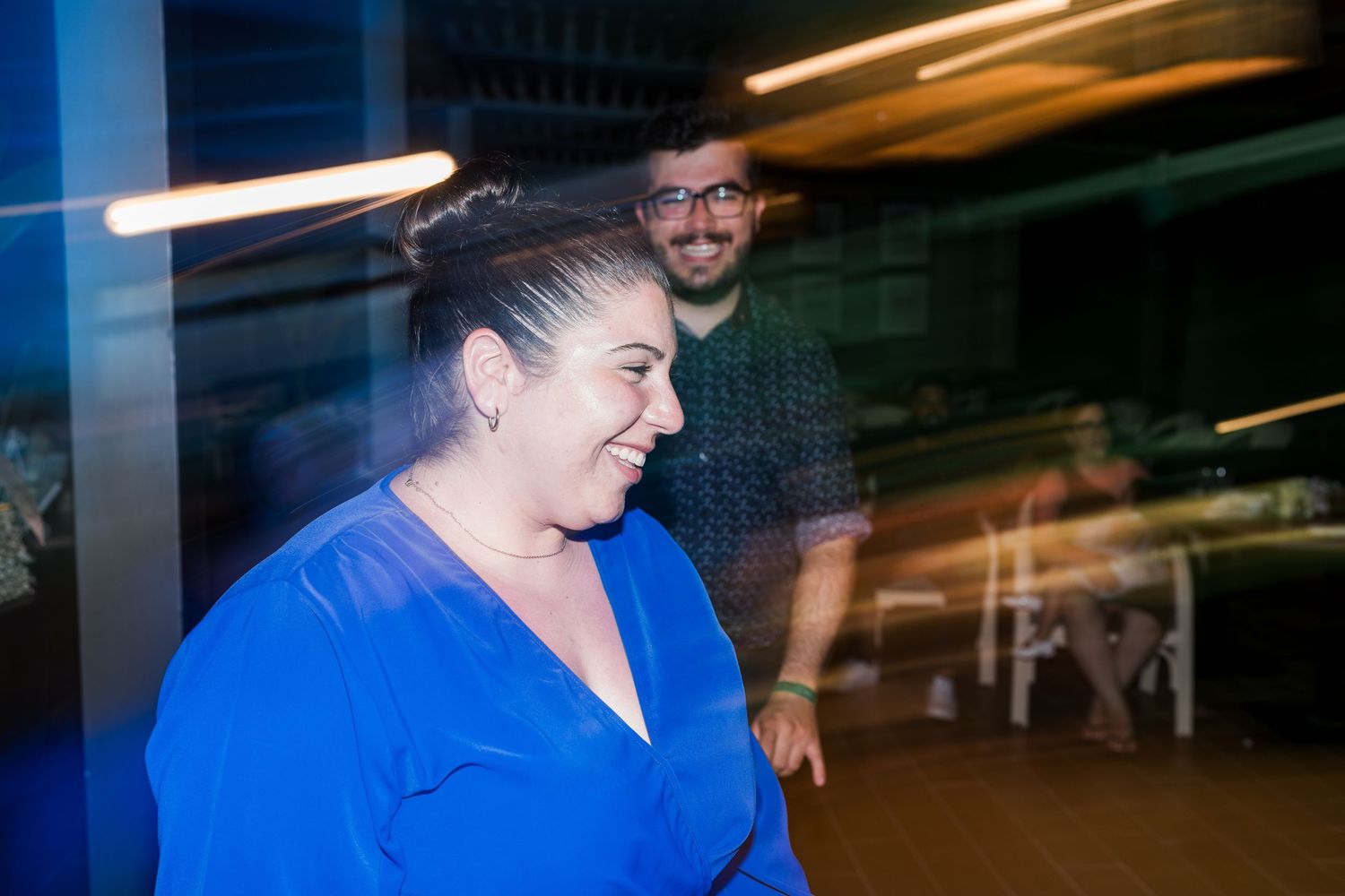 Smiling wedding guest in blue dress captured in motion at the reception venue.