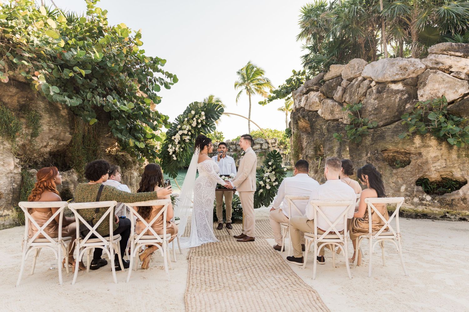 Xcaret Arte Wedding - Intimate outdoor wedding ceremony with couple at floral arch altar