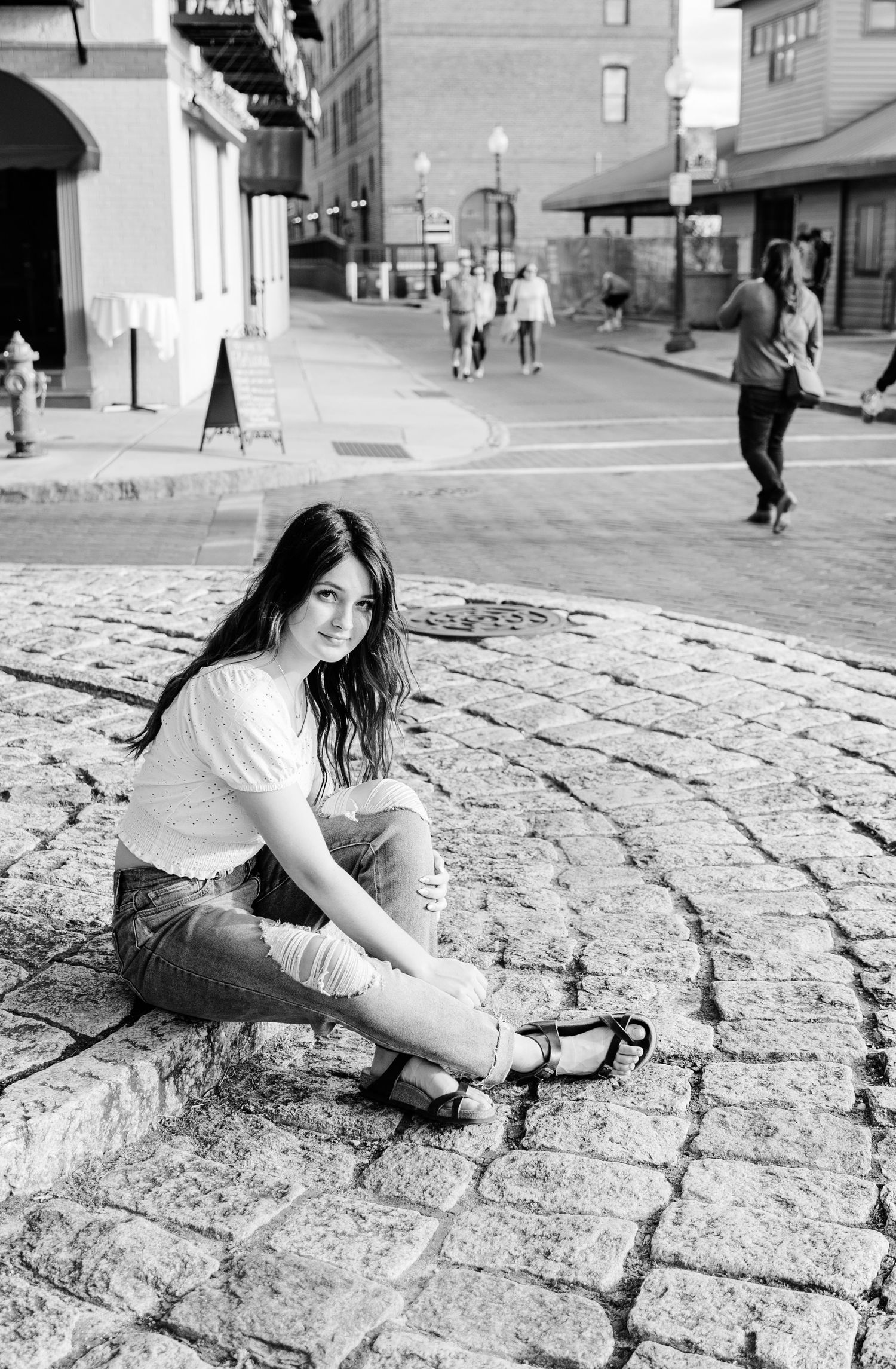 dramatic urban black and white photograph of girl on sidewalk with brick streets in Wilmington, NC