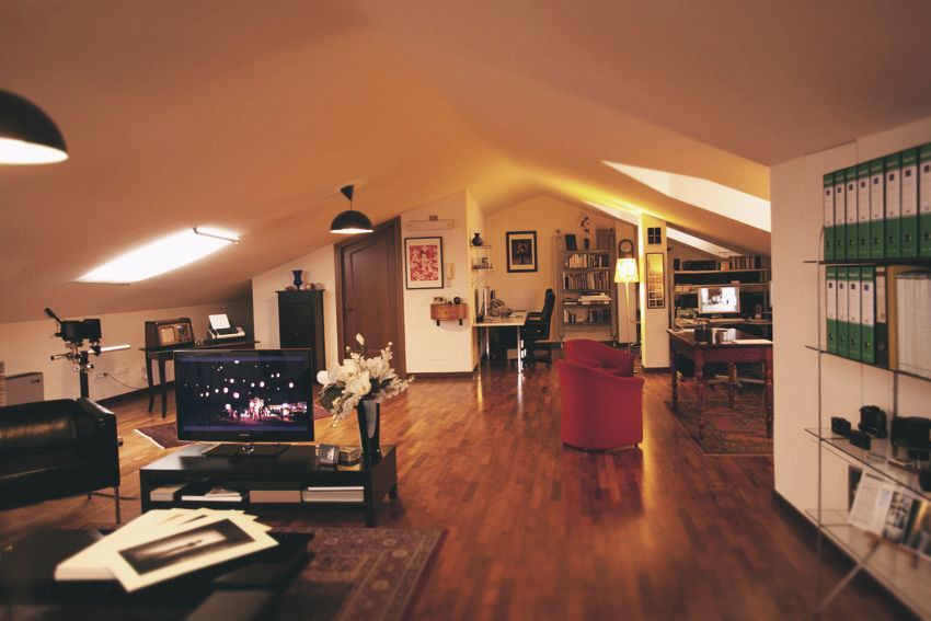 Modern home office setup in converted attic space with wooden floors and bookshelves.