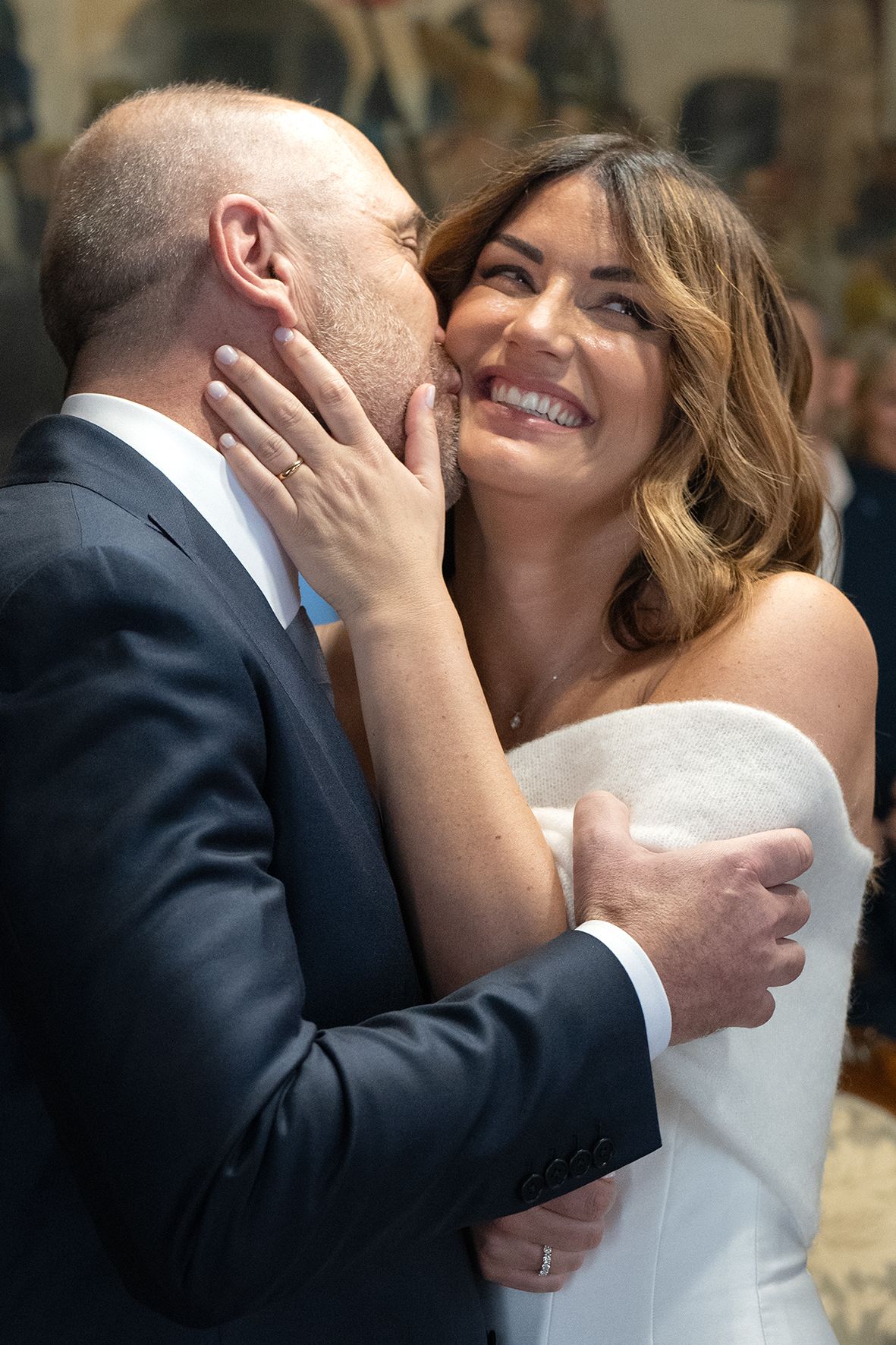 A joyful embrace between newlyweds, with the bride in a strapless white dress laughing during an intimate moment.