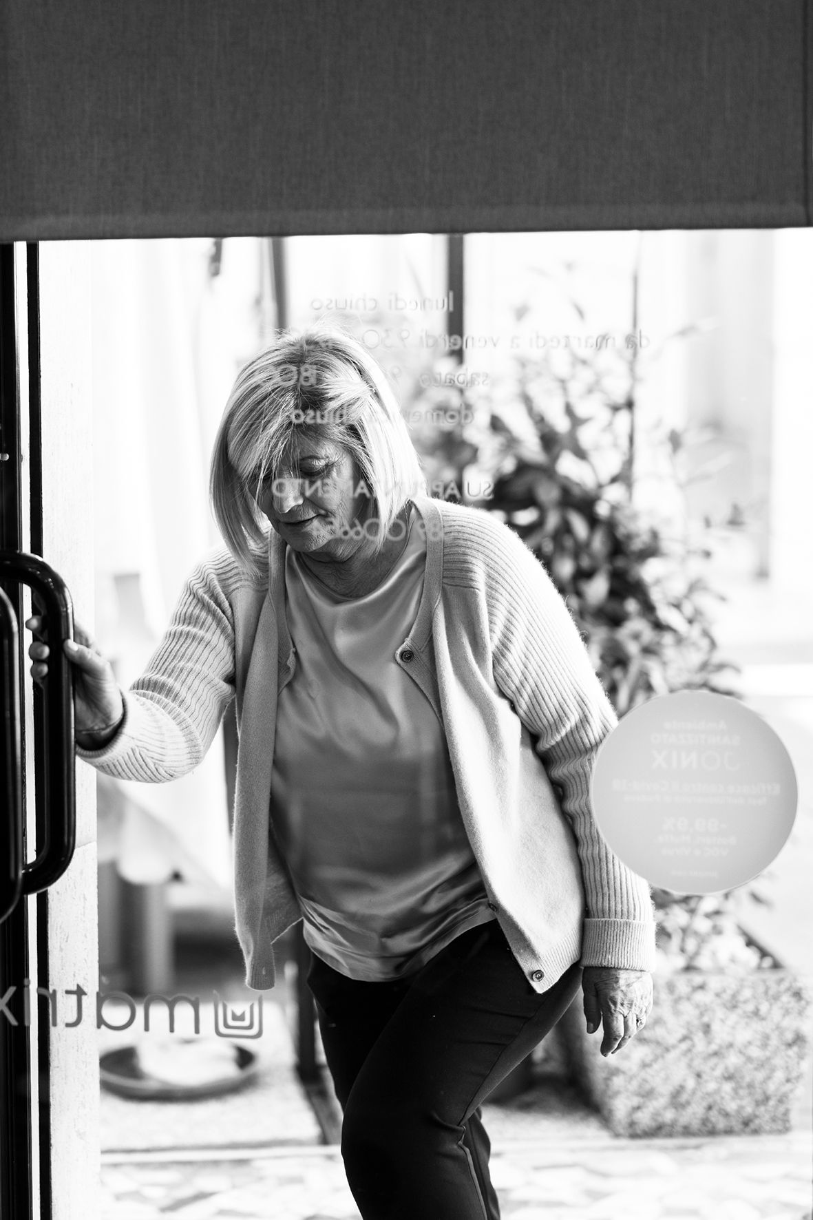 Black and white photo of someone moving indoors with a balloon while wearing a comfy sweater and casual attire.