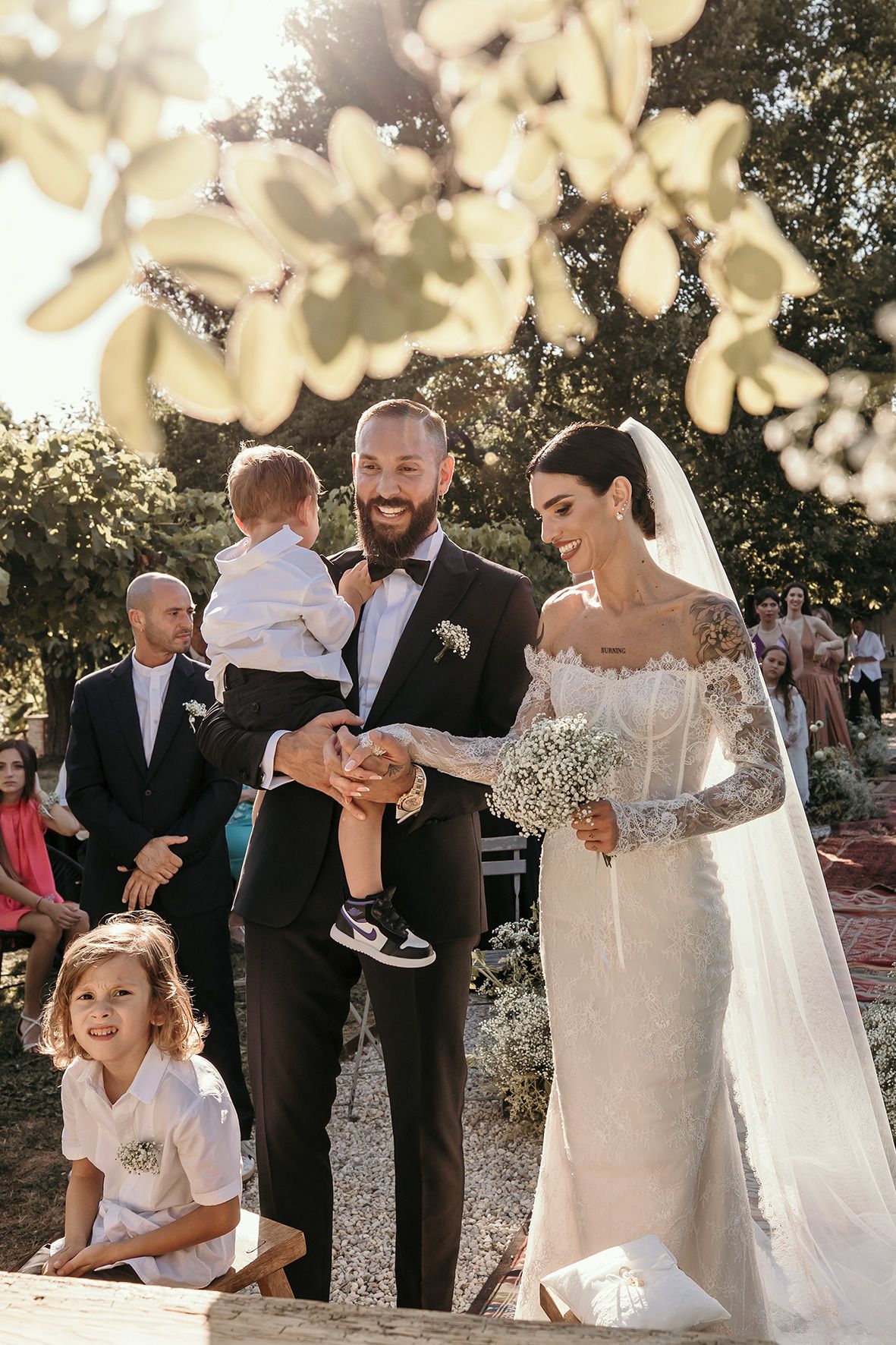 Beautiful outdoor wedding ceremony in a garden setting filled with warm sunlight filtering through tree branches.