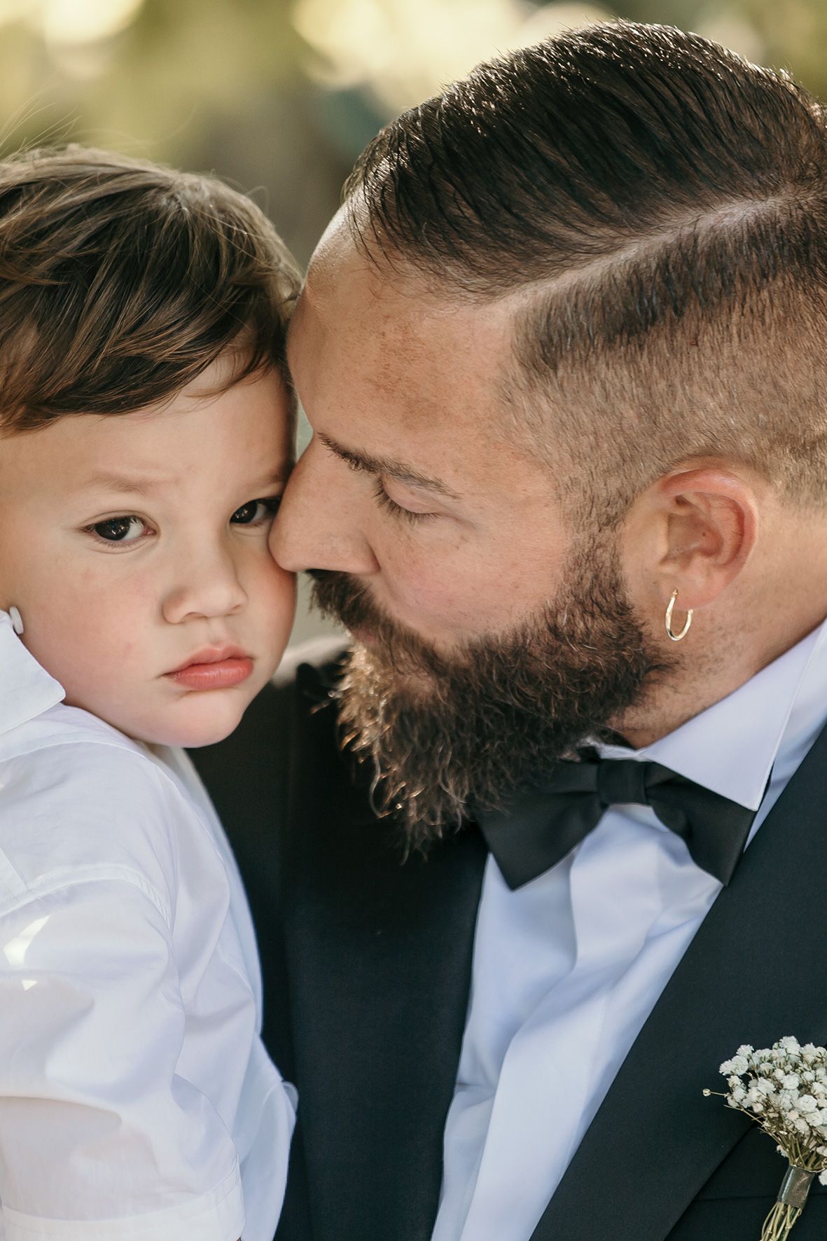 Close up photo of parent and small child at formal event wearing white shirts and black bow tie.