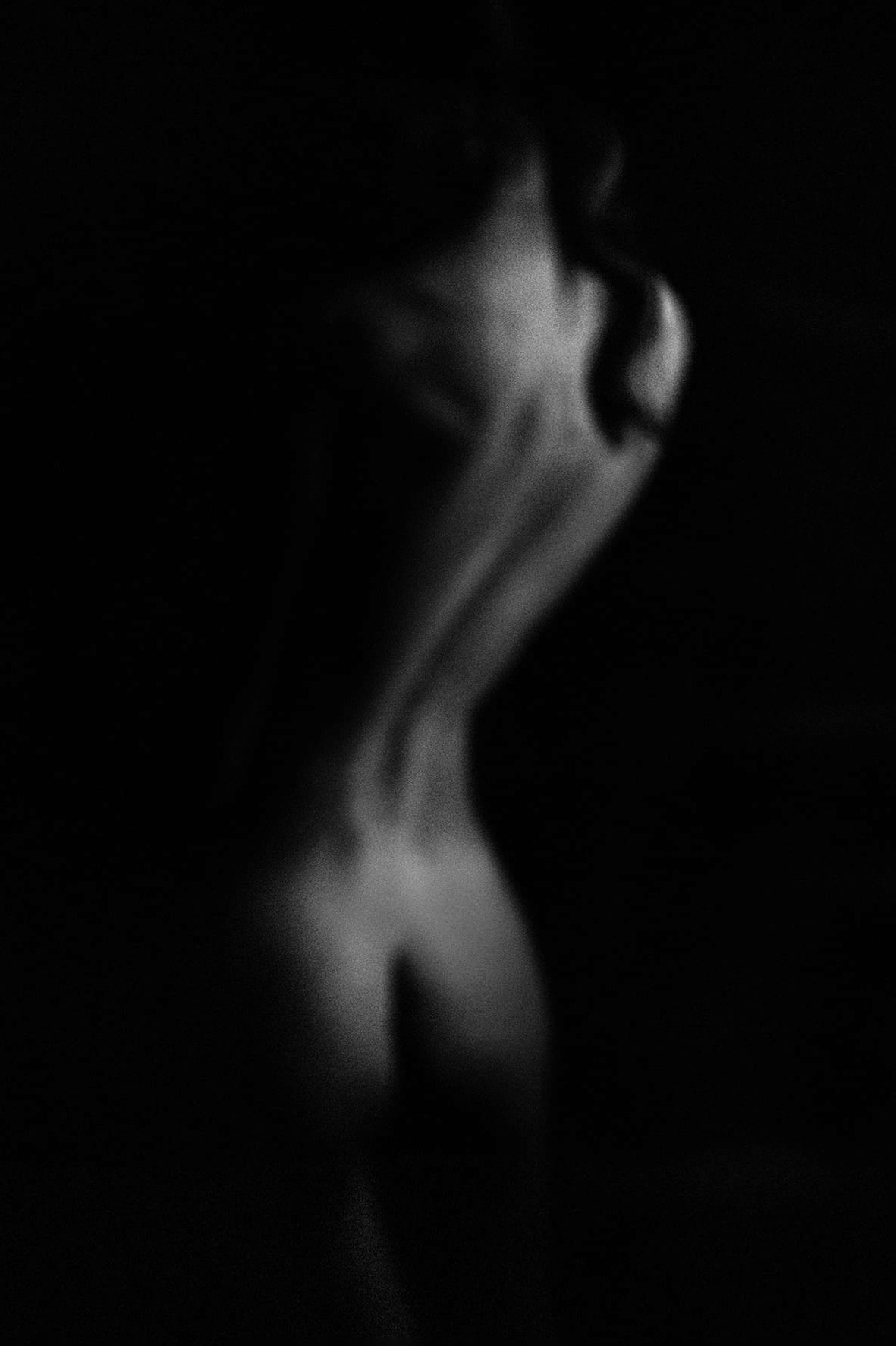 Artistic black and white silhouette of a nude figure with a flowing ethereal form against dark background.