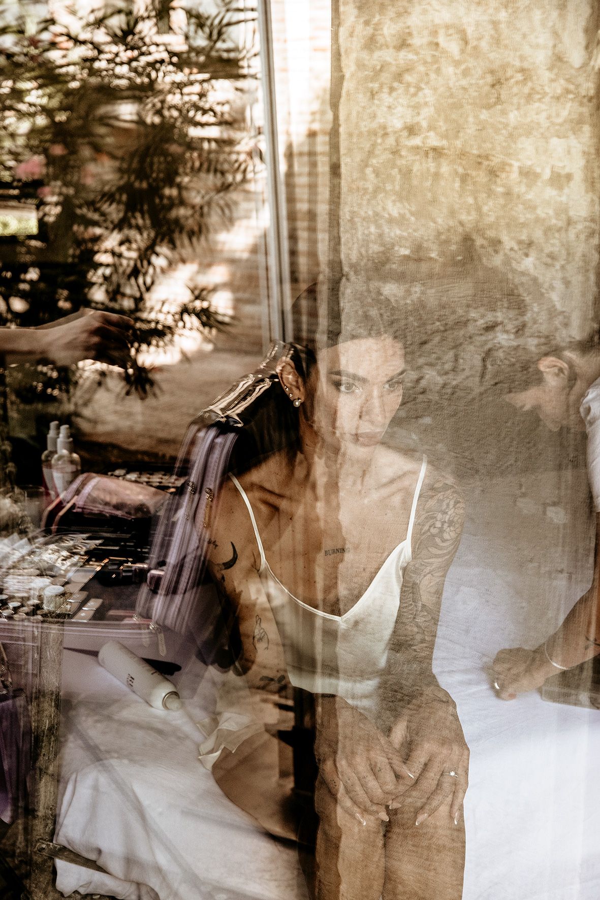 Artistic double exposure photograph showing ethereal layers of shadows and reflections through window glass.
