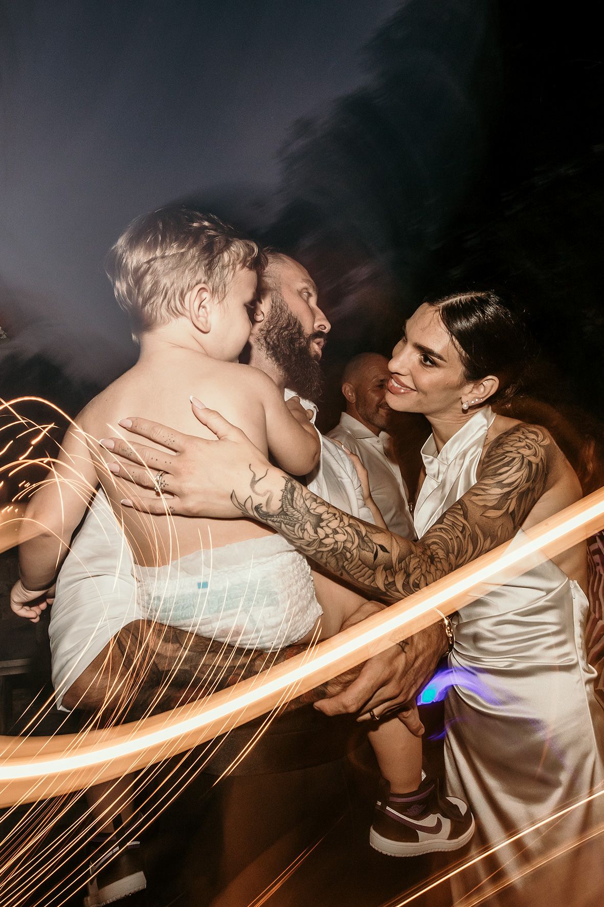 Happy couple dancing and celebrating together at a wedding reception with glowing light trails in the background.