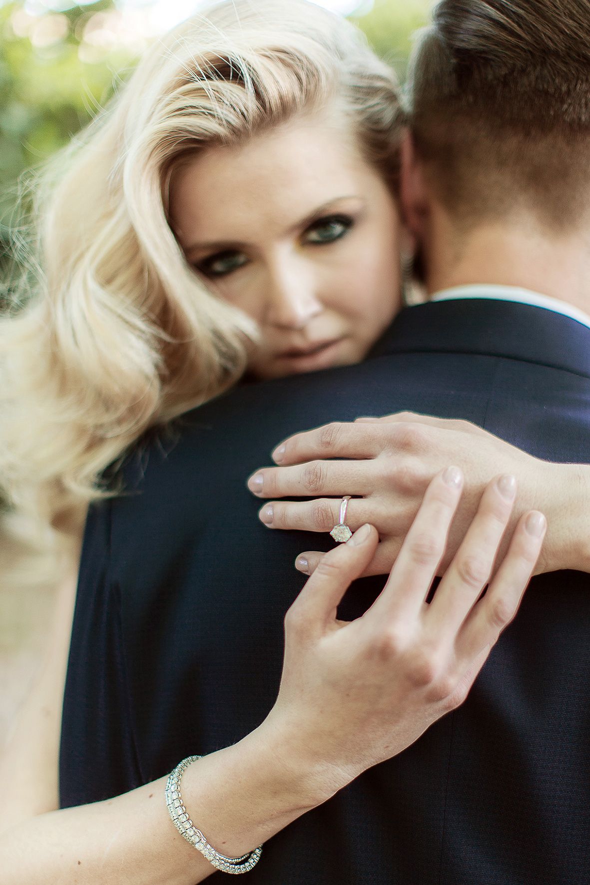 Close up of an intimate wedding moment showing hands embracing with diamond ring and bracelet details.