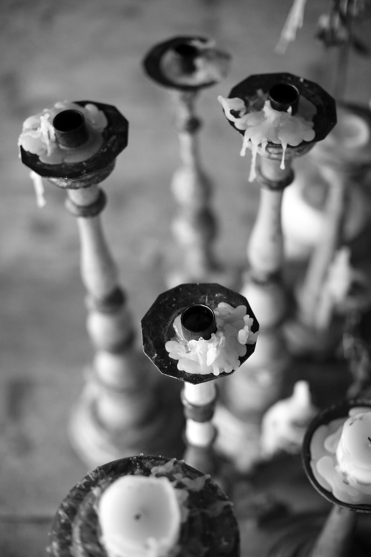 Black and white photograph of rustic candlesticks with melted wax drippings viewed from above.