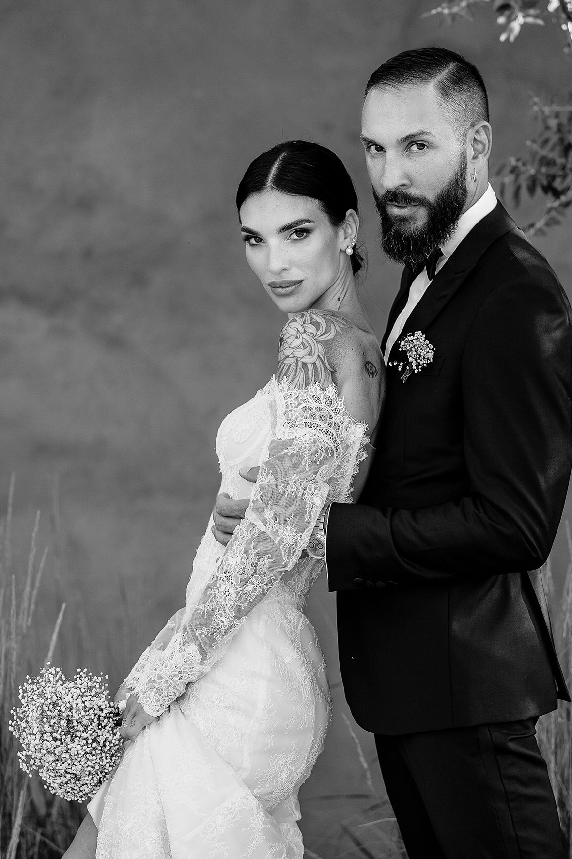 Black and white elegant wedding portrait of couple with bride in lace gown and groom in dark suit.