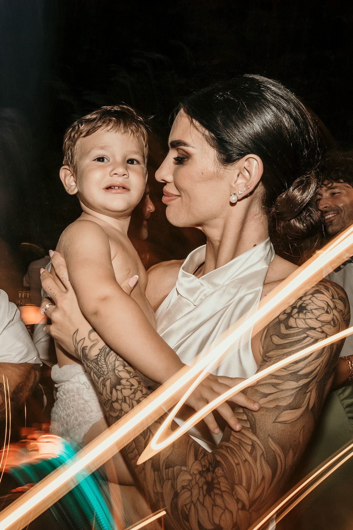 A tender moment captured at an event showing parent and child embracing in warm lighting with artistic light streaks.