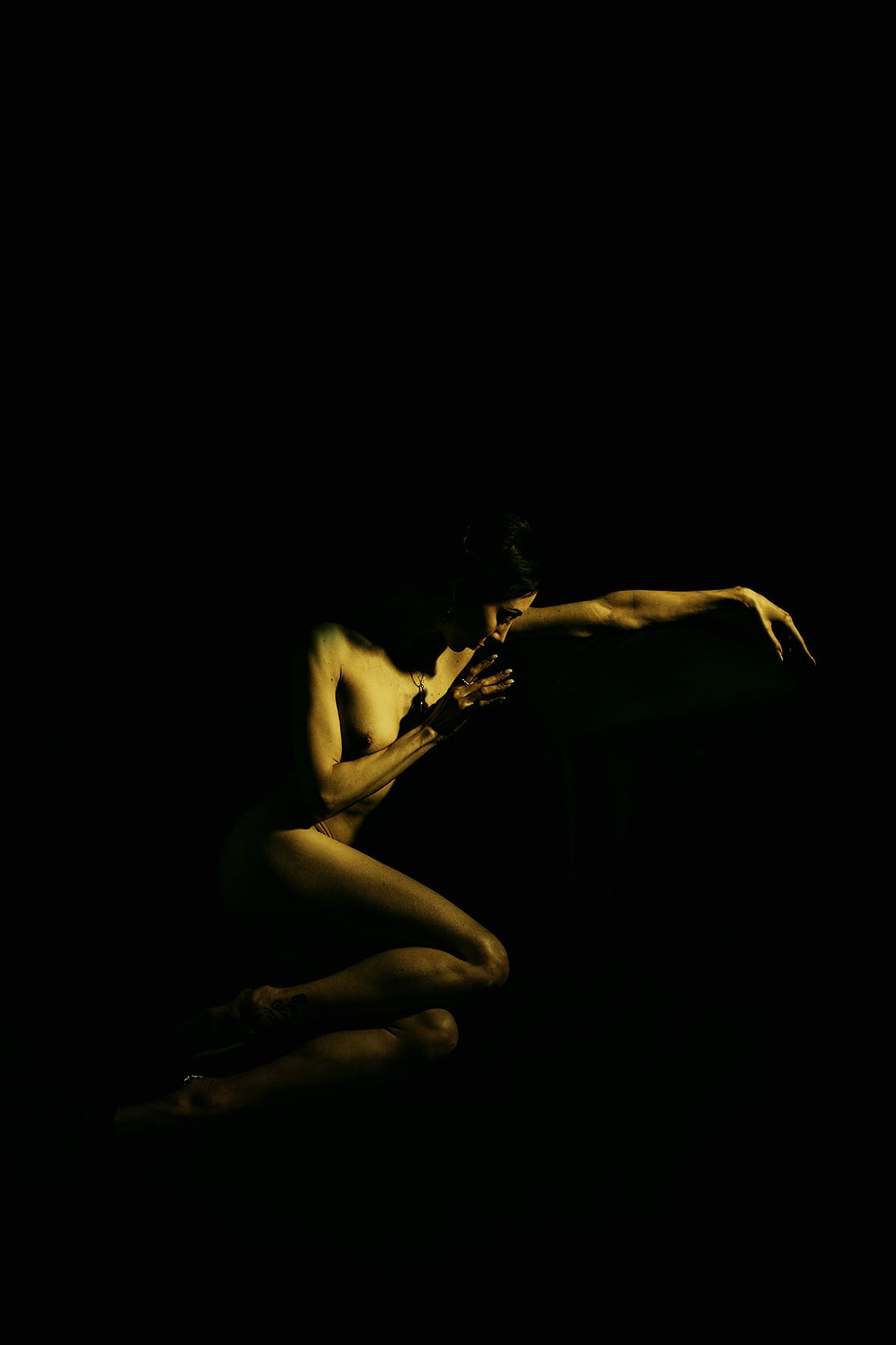 Artistic silhouette of a figure in dim yellow lighting against dark background creating dramatic contrast.