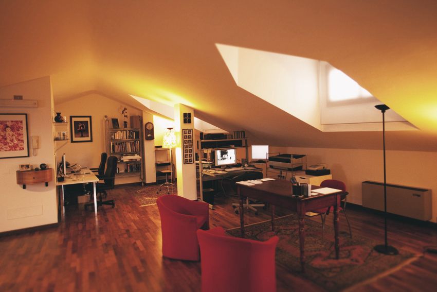 Contemporary attic living space with sloped ceiling and red accent chairs.