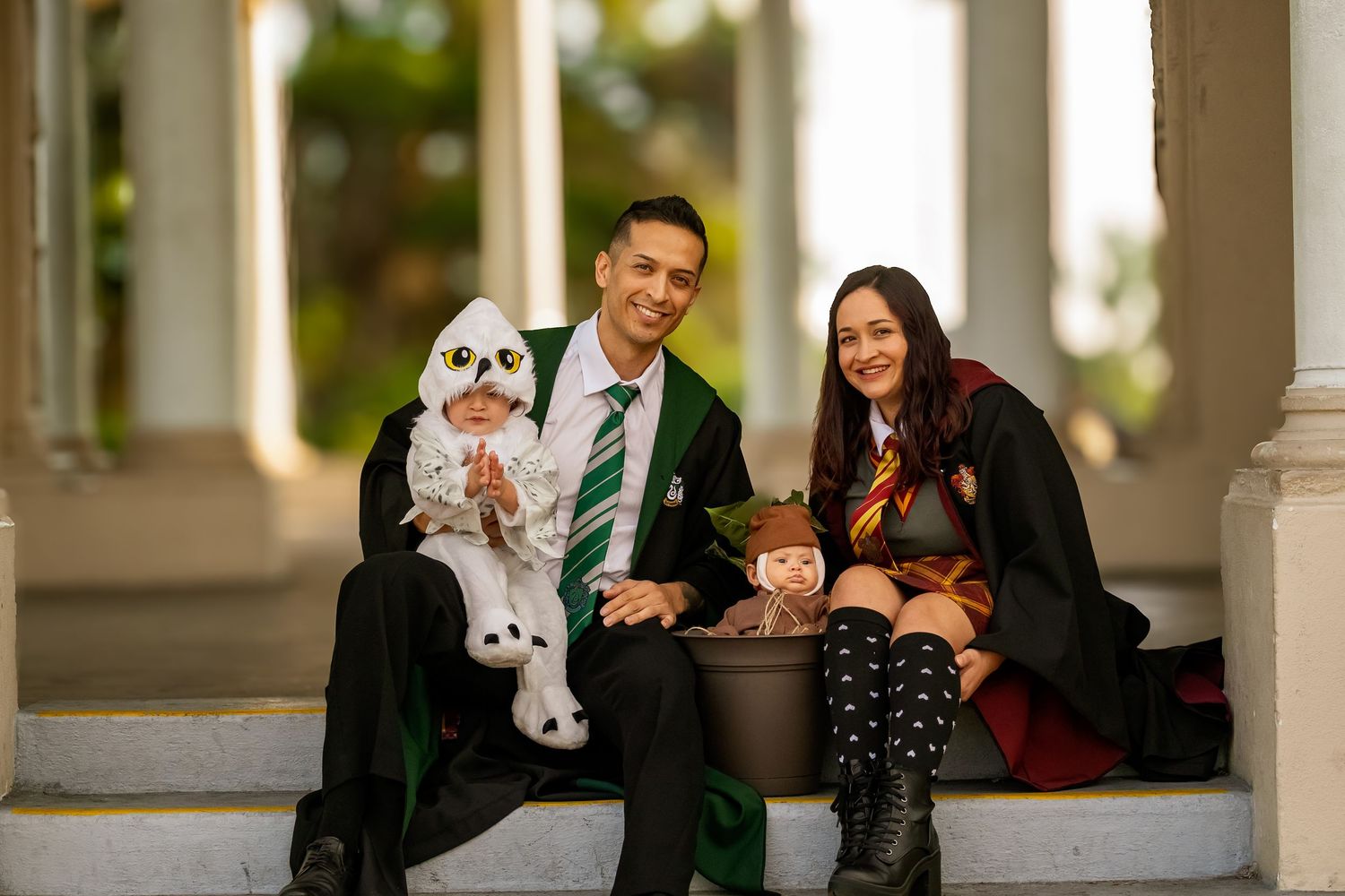 Family photo with parents in Hogwarts graduation robes, posing with children in magical creature costumes.