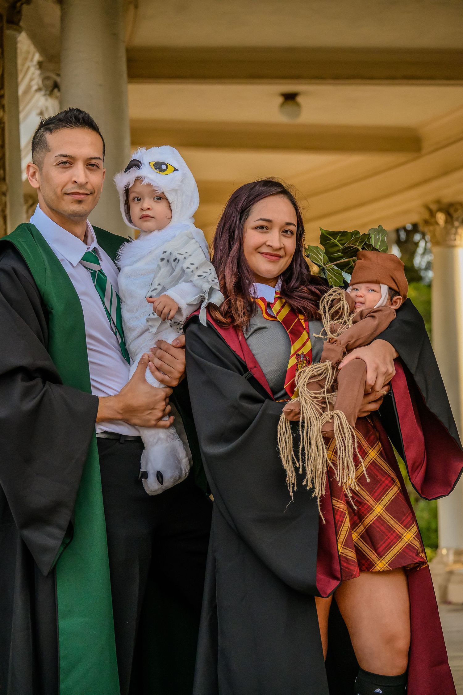Family photo with parents in Hogwarts graduation robes, posing with children in magical creature costumes.