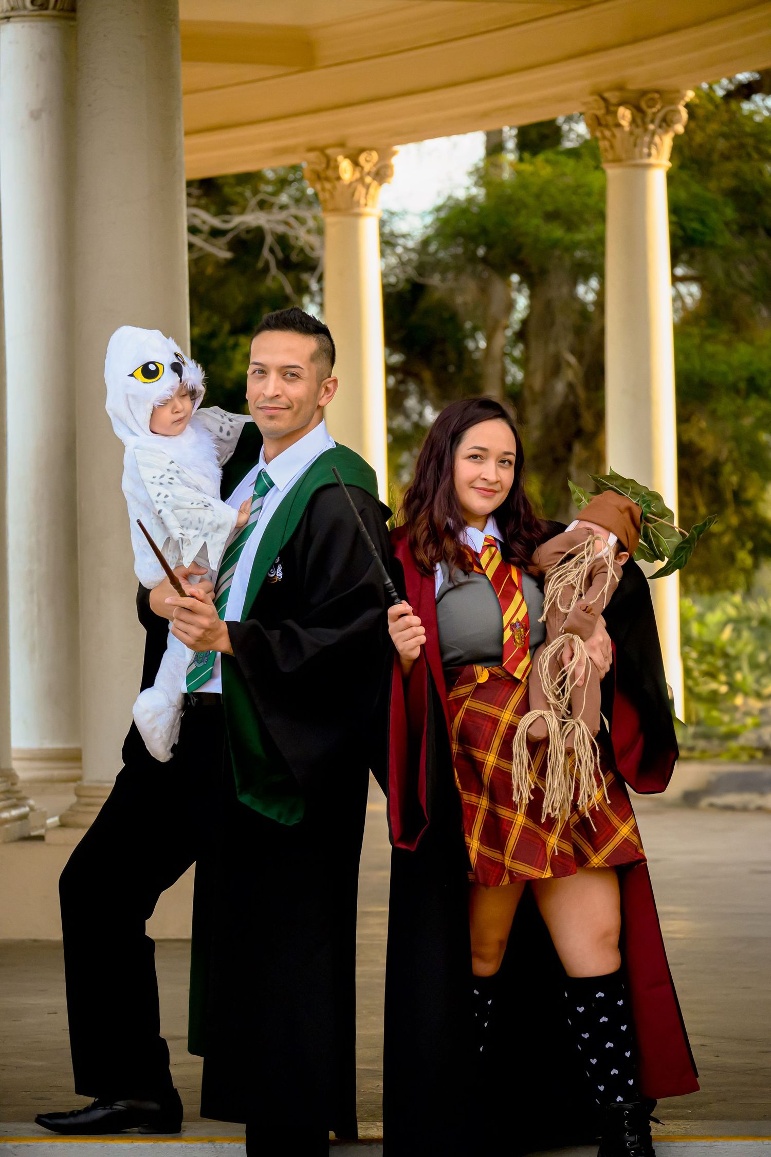 Family photo with parents in Hogwarts graduation robes posing with children in magical creature costumes.
